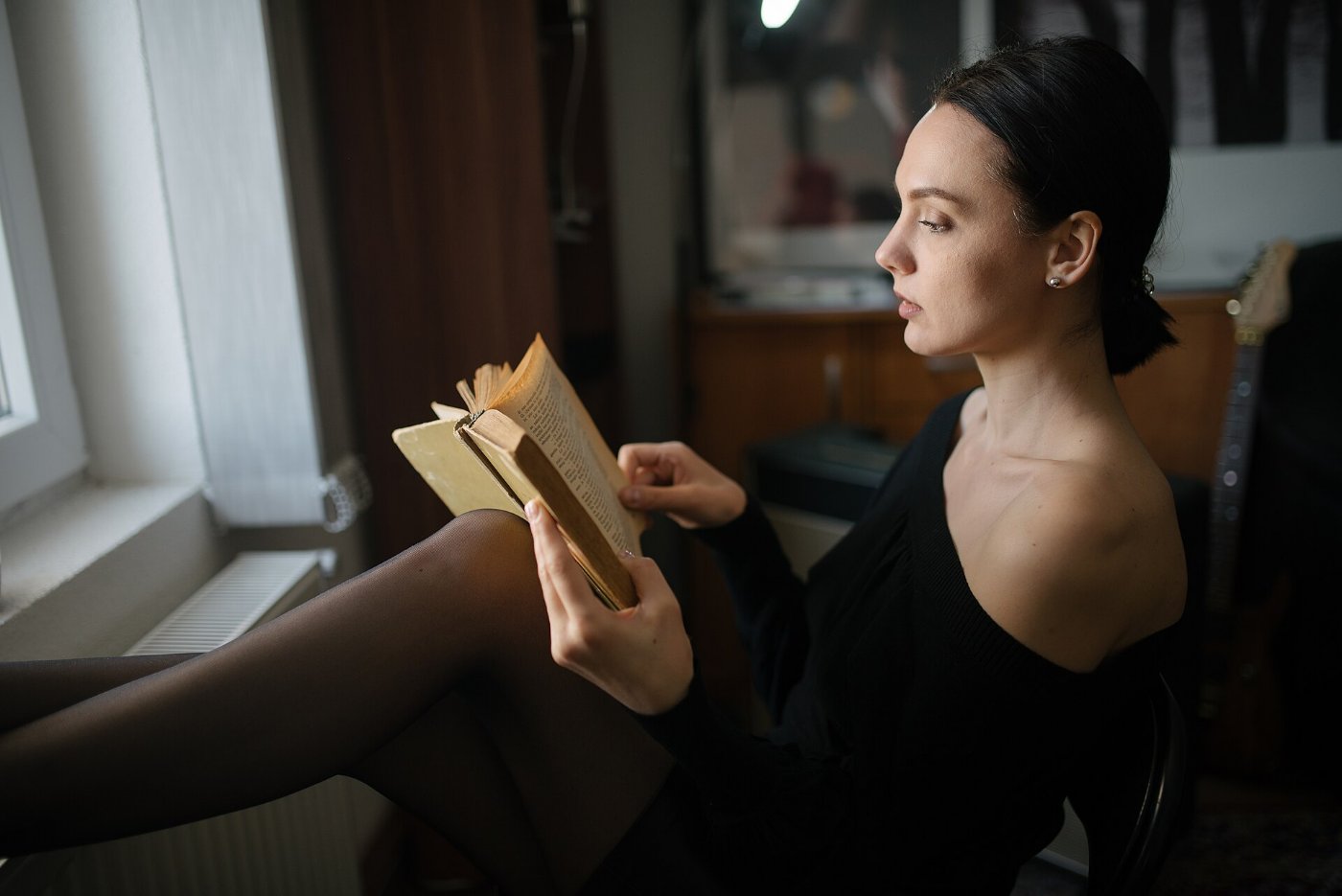A woman reading a book by a window