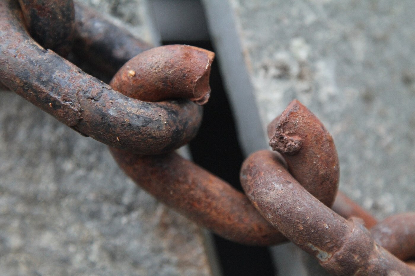 A rusted chain with one link cut through