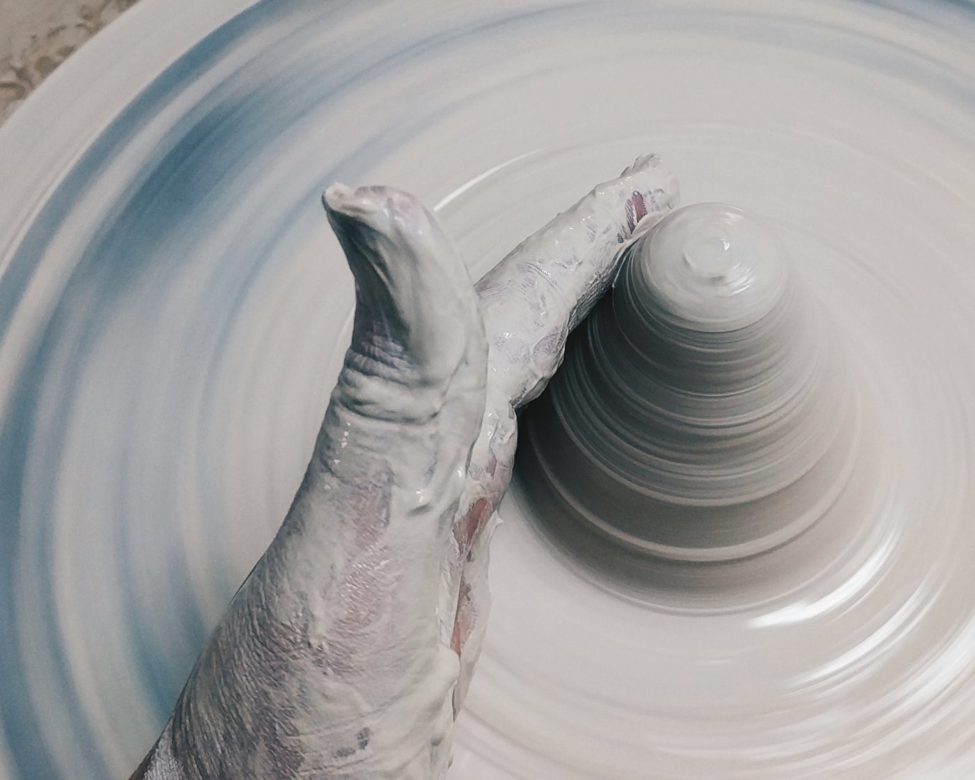 A potter’s hands shaping fresh clay on the wheel